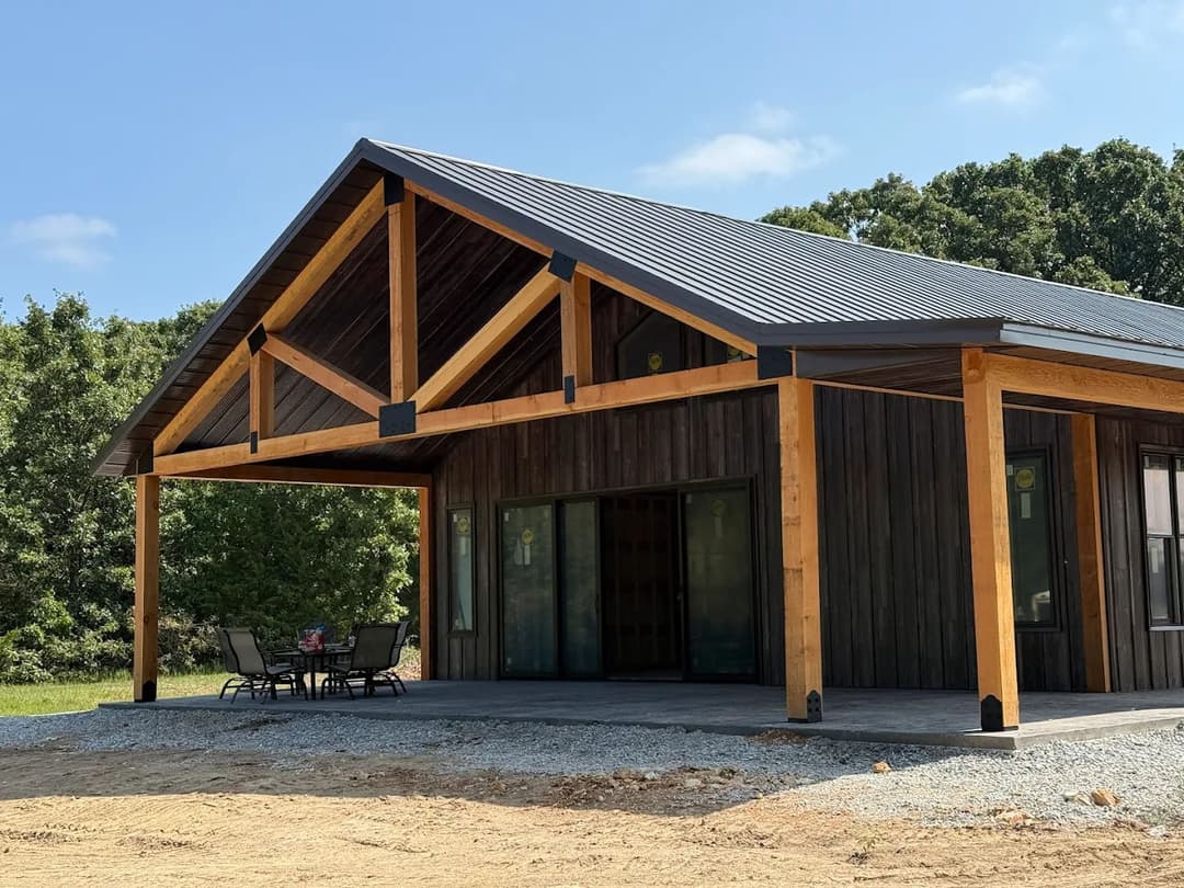 Modern ranch-style house with wood accents and a metal roof, featuring a patio area.